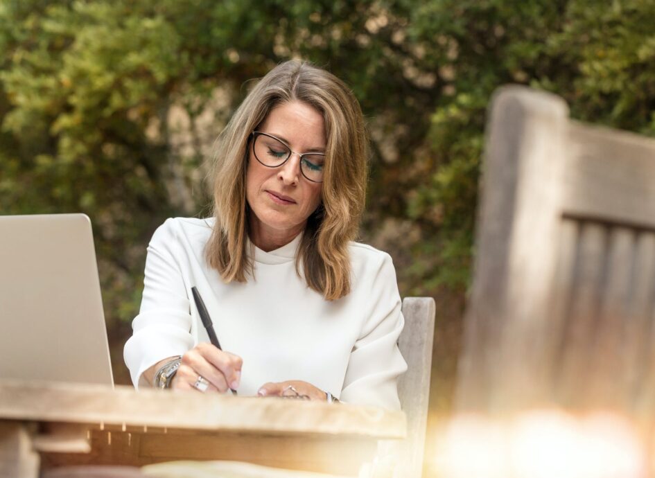 woman sitting on gray chair while writing on table