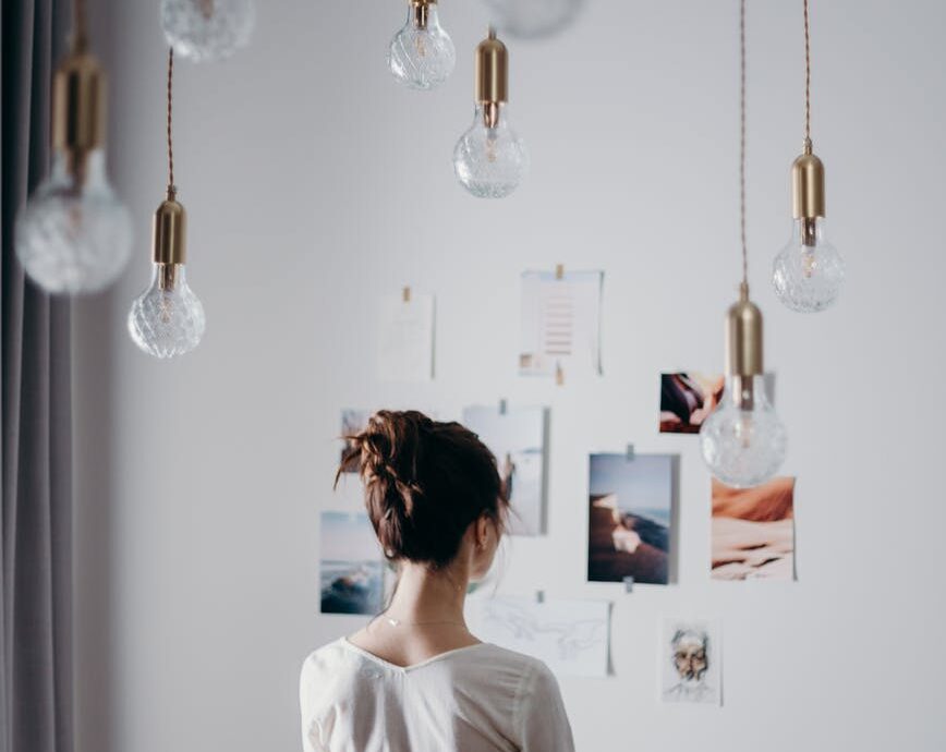 woman under pendant lights looking at the photo on the wall