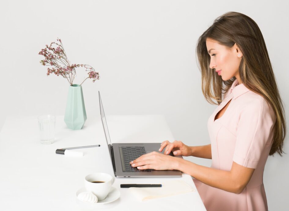 woman in pink dress using laptop computer